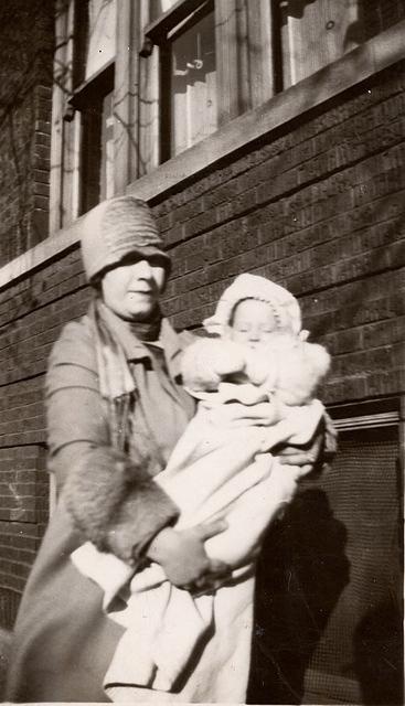 Leona Yellen Raskin holding Minette Raskin Akman in front of their home.