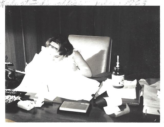 Linda Clutz Cohn working at her father's desk at his office, 1963