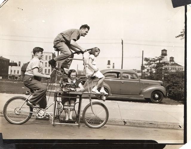 Charlie Steinlauf family on a bike.  Wife, Lillian Shaffer Steinlauf at the sewing machine and kids Fred and Ruth.