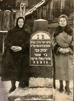 Sisters, Devorah Kvayke and Rochla Teperowicz standing by the matzeva headstone of their father, Yitzchak Tzvi "Hirsh" (Icko Gerszko).  See notes.